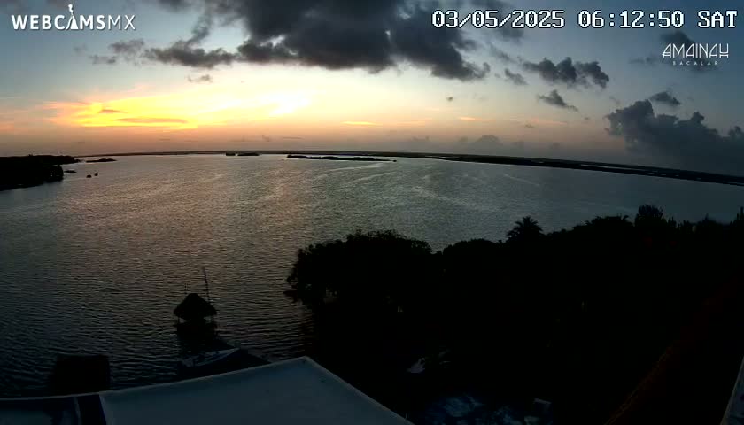 An elevated view shows a calm body of water at sunset under a partly cloudy sky.