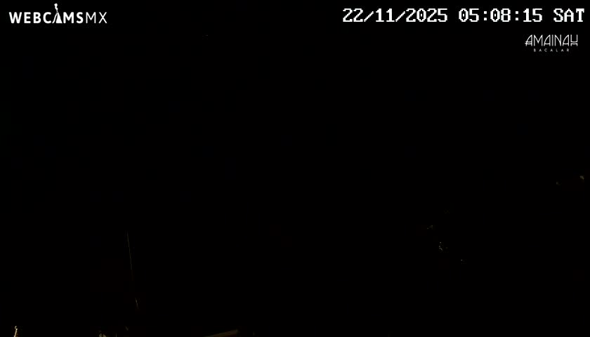 The image is overwhelmingly black with a few faint, scattered light specks discernible towards the bottom and right, rendering any outdoor scene or weather conditions indistinguishable.