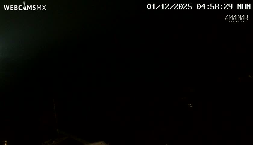 The image displays an extremely dark outdoor scene at night, with only faint outlines of objects visible at the bottom under clear conditions.