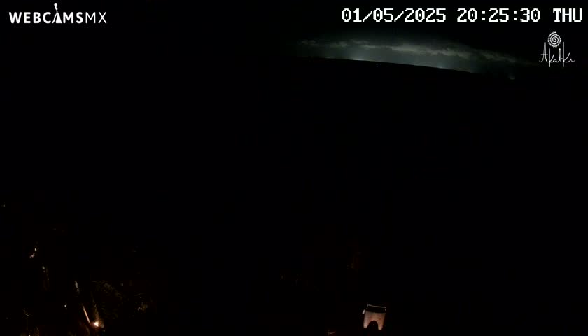 A nighttime, possibly stormy, outdoor scene shows a dark horizon with a faint, bright band of light in the distance.