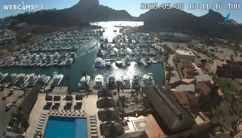 A sunny day overlooking a marina filled with boats, a swimming pool, and a collection of buildings.