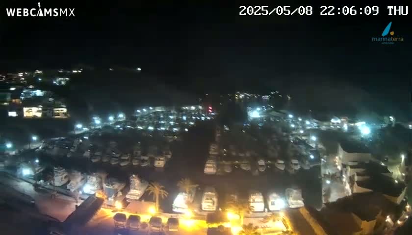 A nighttime aerial view of a marina filled with boats illuminated by lights.