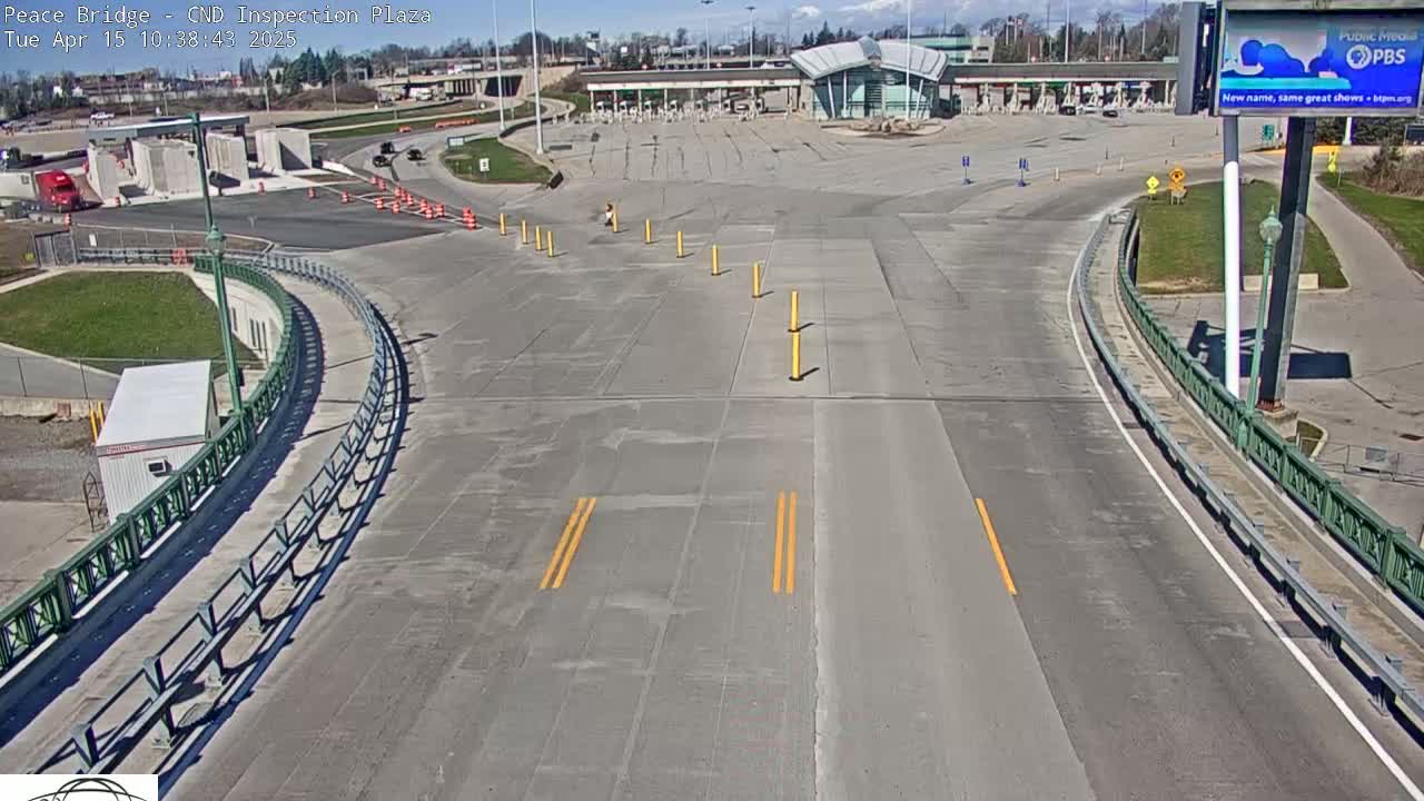A mostly empty highway inspection plaza with a modern building under a sunny sky.