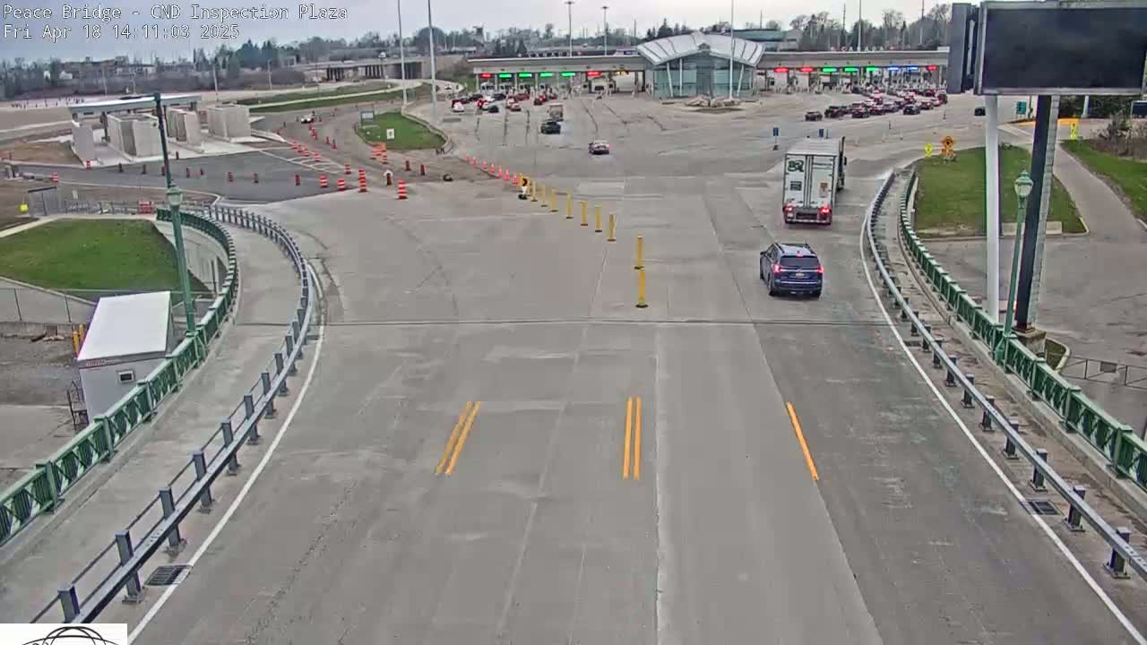 A mostly empty highway approaches a border inspection plaza under a partly cloudy sky.