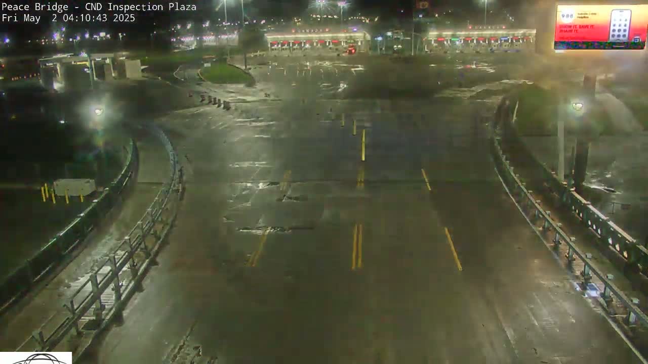 A wet, empty roadway at night curves around a mostly empty inspection plaza, illuminated by artificial lights.
