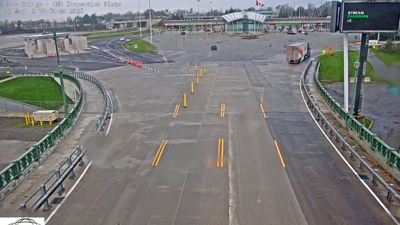 A mostly empty border crossing inspection plaza on a cloudy day with a single semi-truck visible.