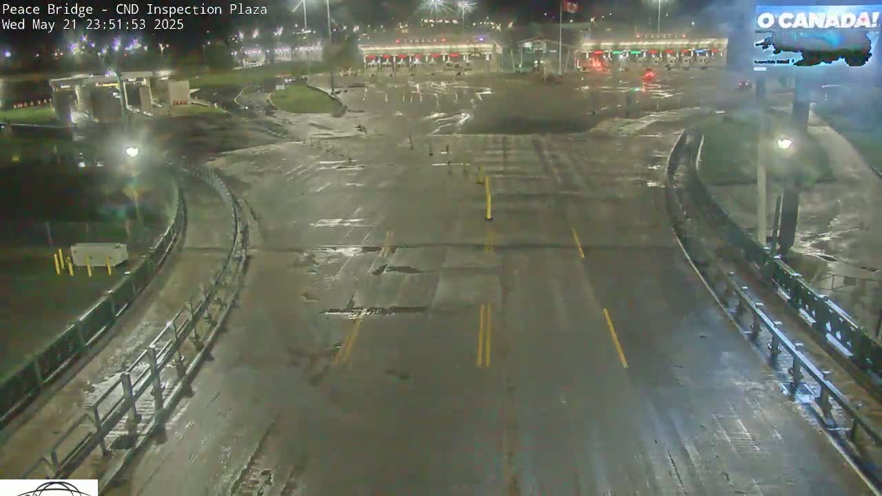 A wet, nighttime view of a mostly empty border crossing inspection plaza with several lanes leading to inspection booths.