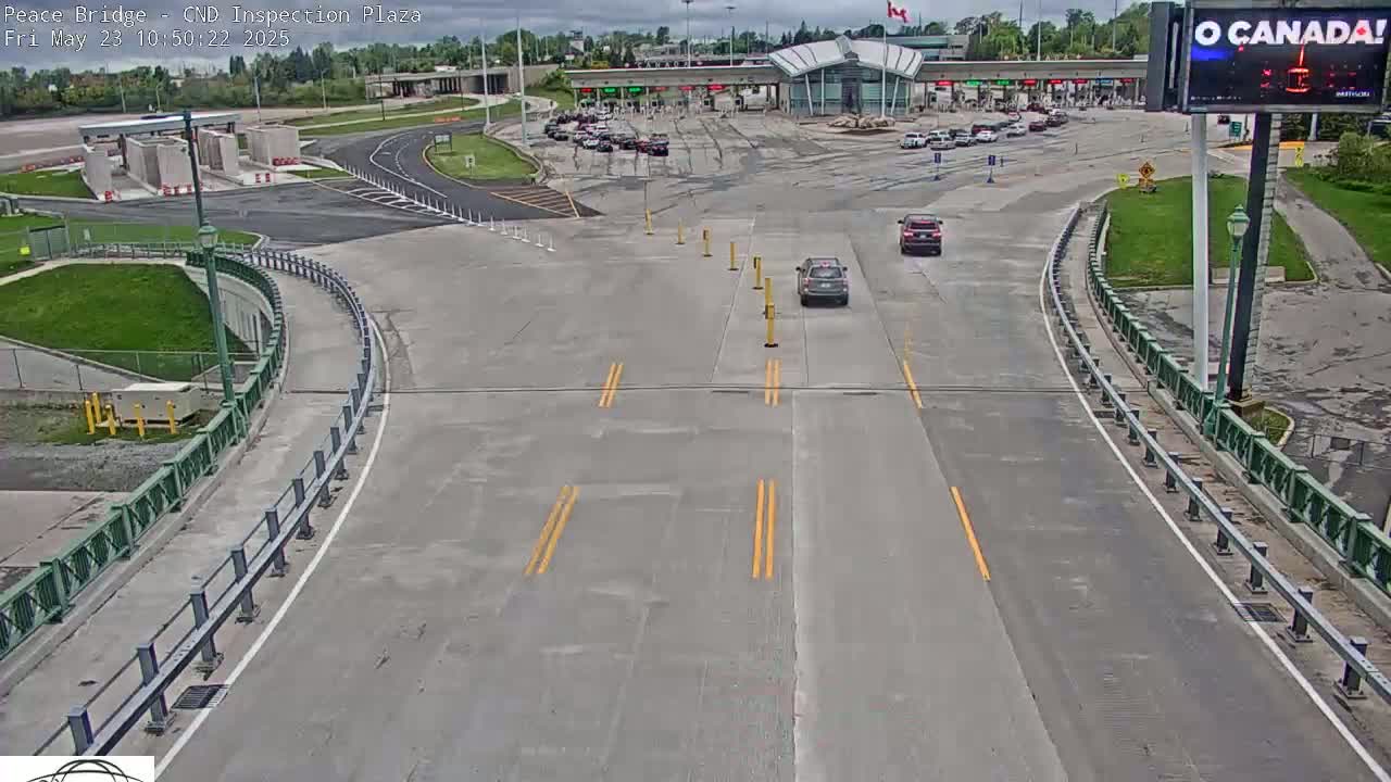 A high-angle view of a roadway leading to a border crossing station on an overcast day, with several vehicles visible.
