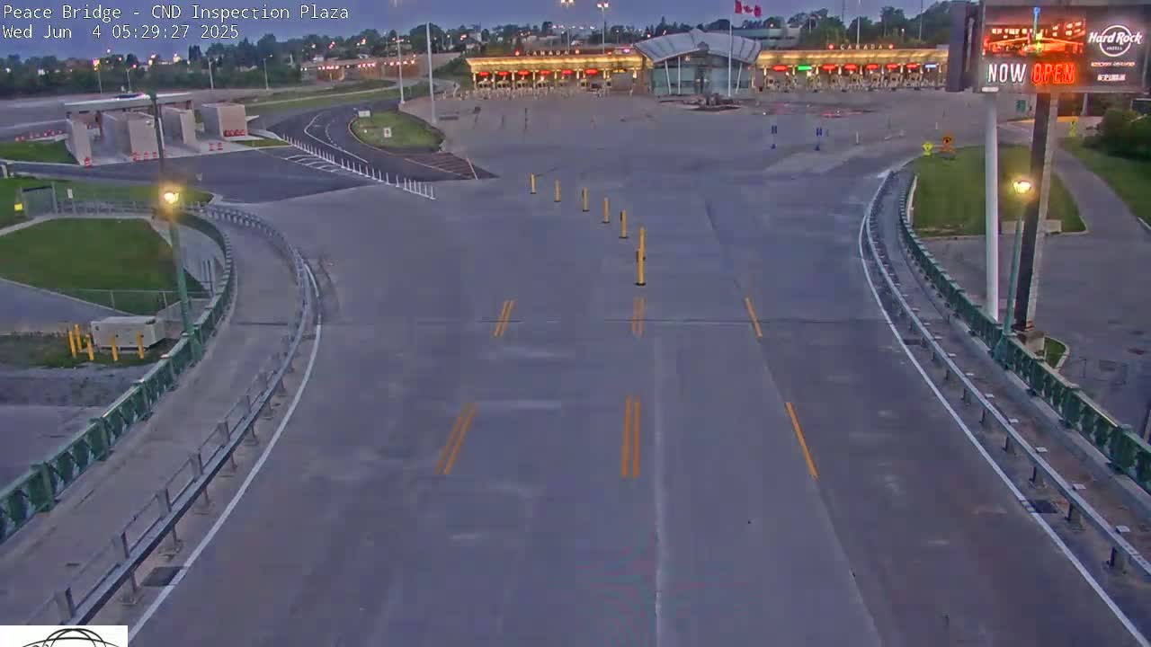 A mostly empty border crossing plaza at dusk, with a roadway curving towards it.