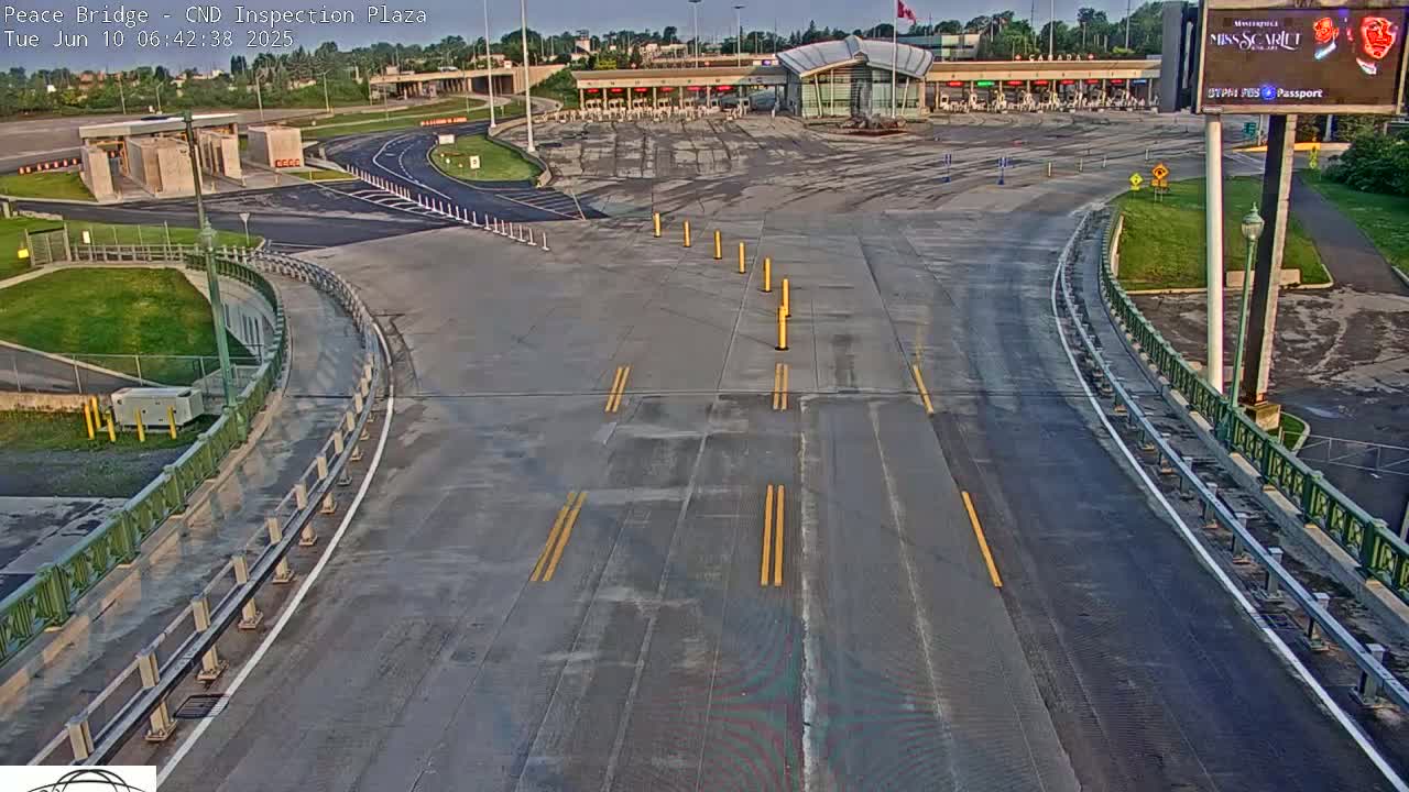 An empty border inspection plaza on a sunny morning, with roadways leading to and from the inspection booths.