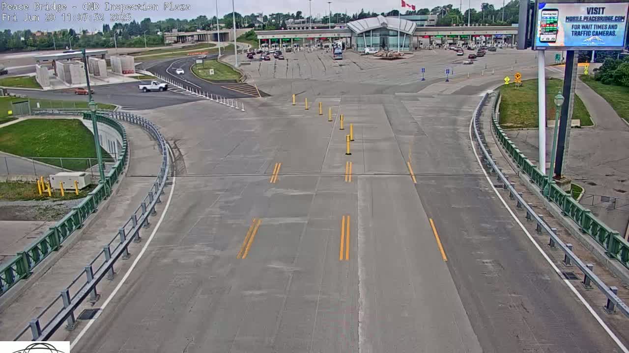A mostly empty border inspection plaza with a few vehicles is seen on a partly cloudy day.