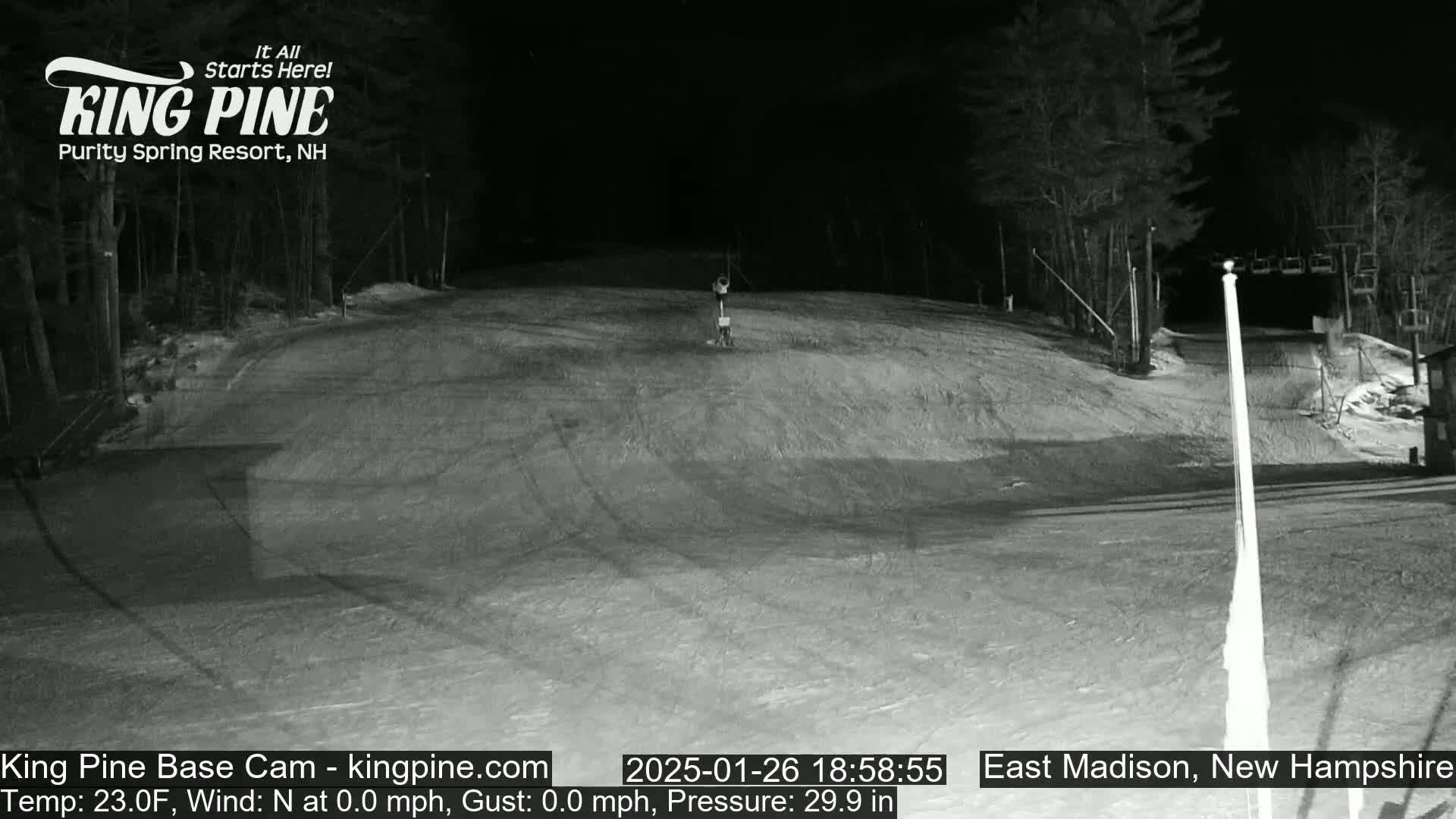 A nighttime, snow-covered ski slope is empty except for a single object near the center.