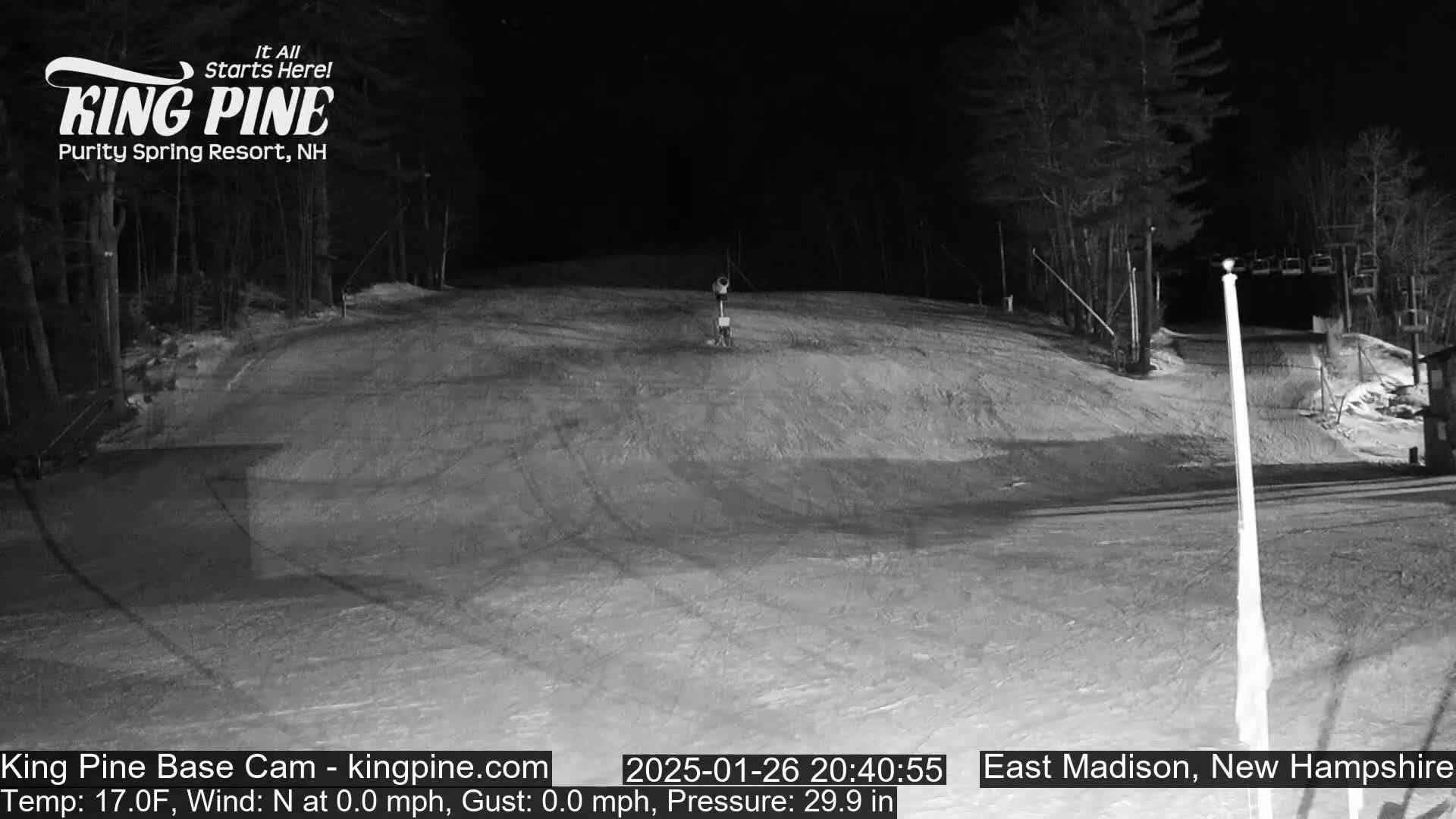 A nighttime, snow-covered ski slope is visible under a clear, dark sky.
