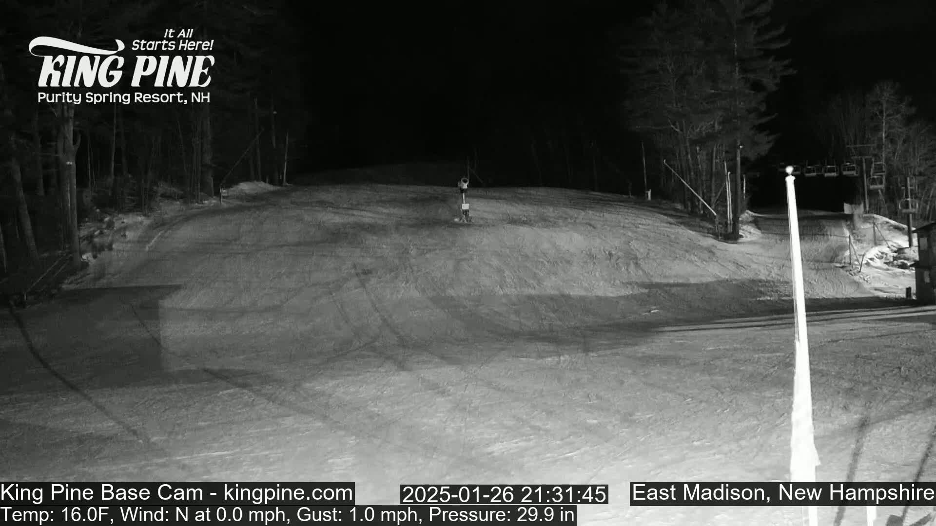 A nighttime, snow-covered ski slope is illuminated, with calm winds and a temperature of 16°F.