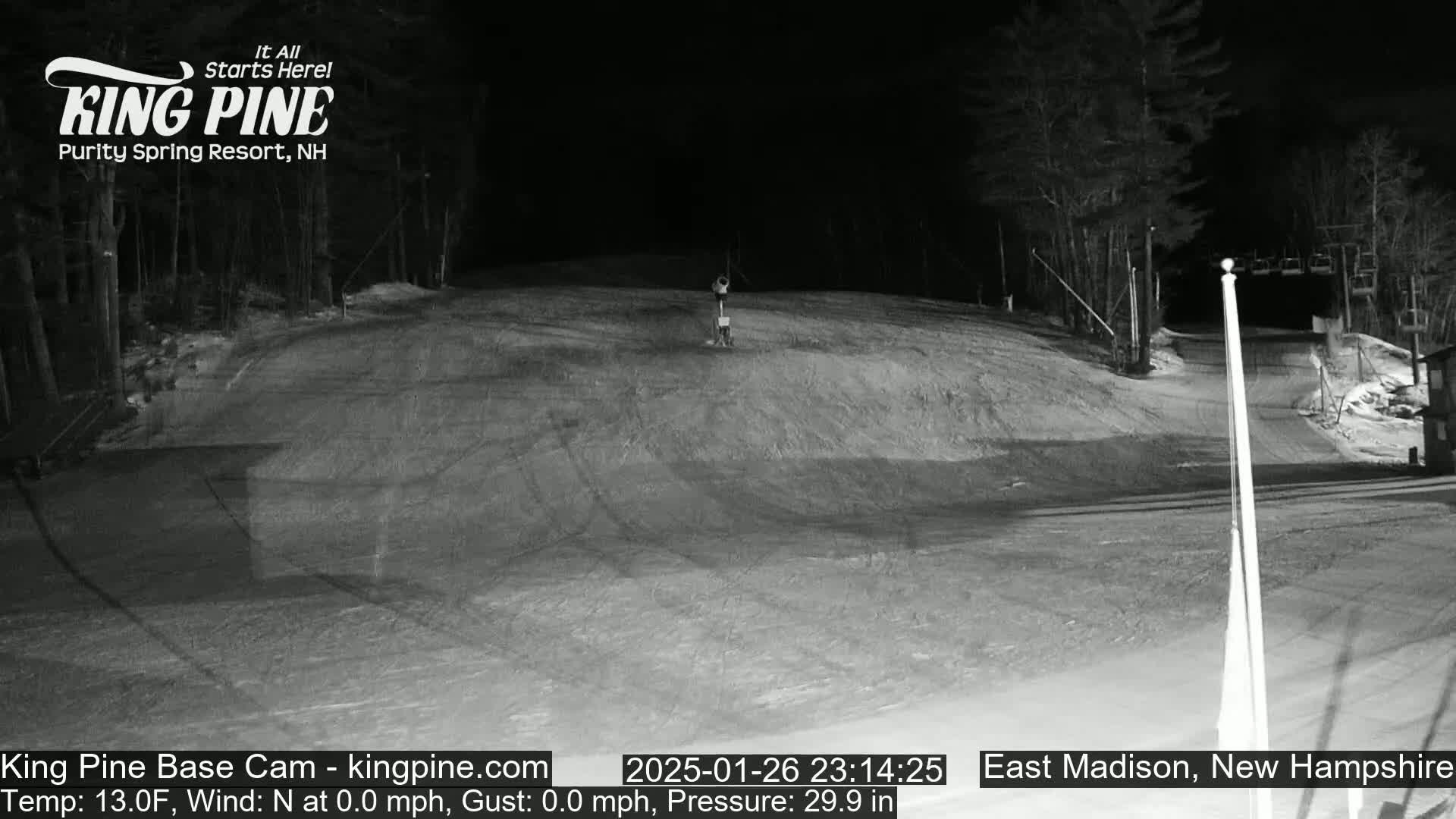 A nighttime, snow-covered ski slope is mostly empty under a clear, dark sky.