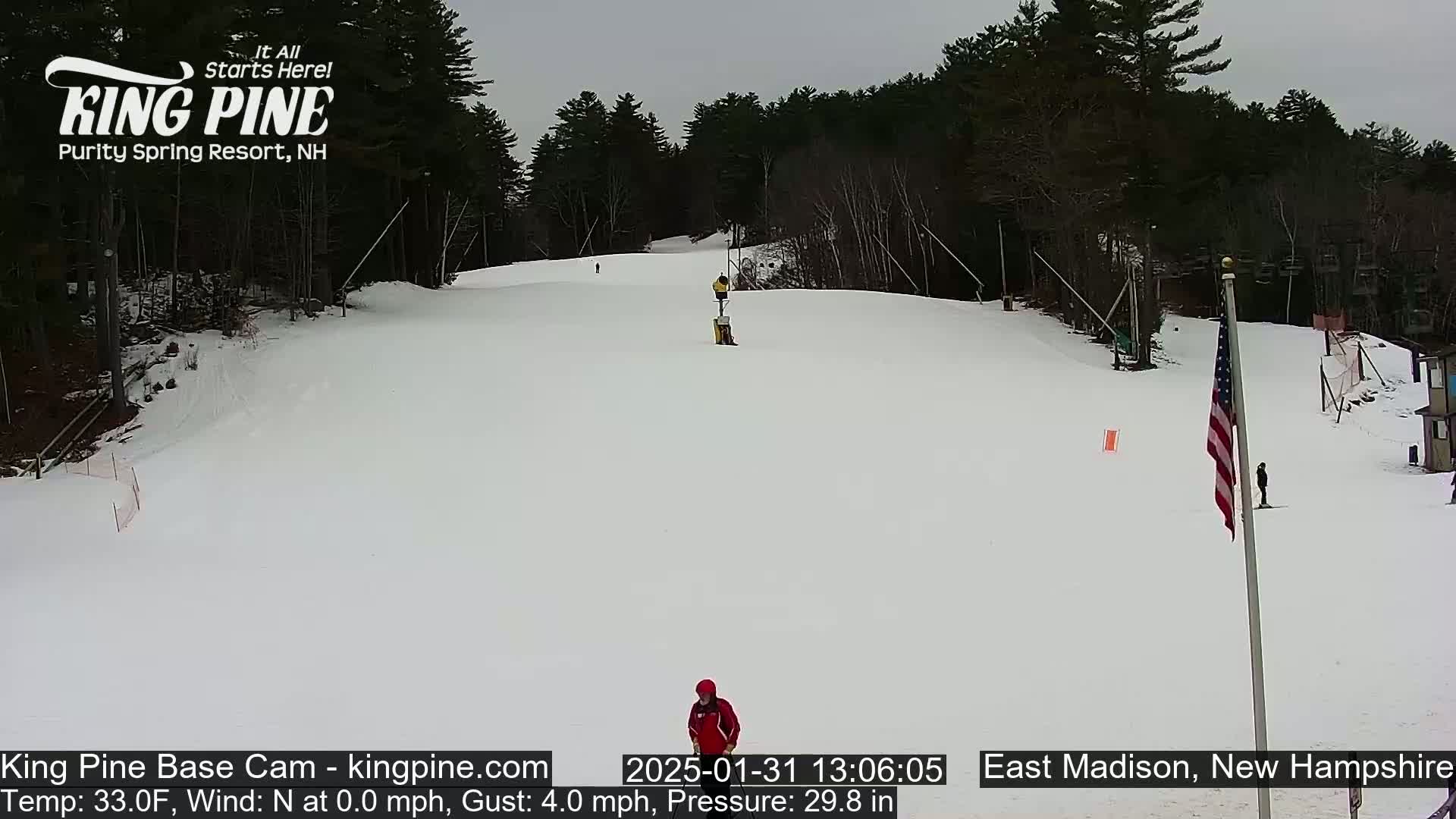 A snowy ski slope is visible, with several skiers present under an overcast sky.