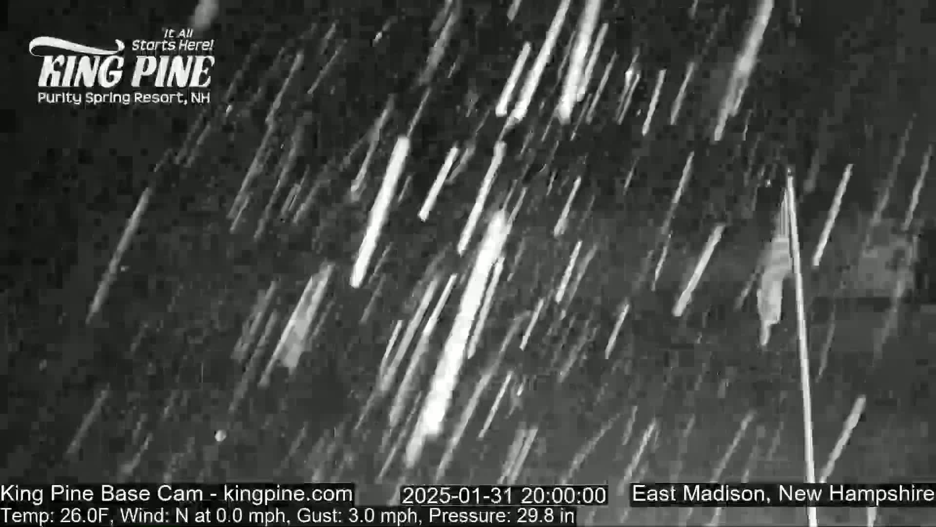A nighttime outdoor scene shows heavy snowfall with a slight wind.