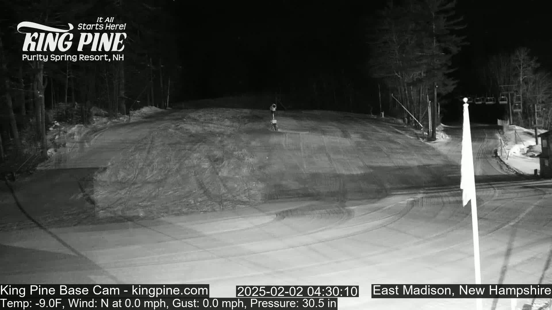A nighttime, snow-covered ski slope is mostly empty except for a lone object near the top.