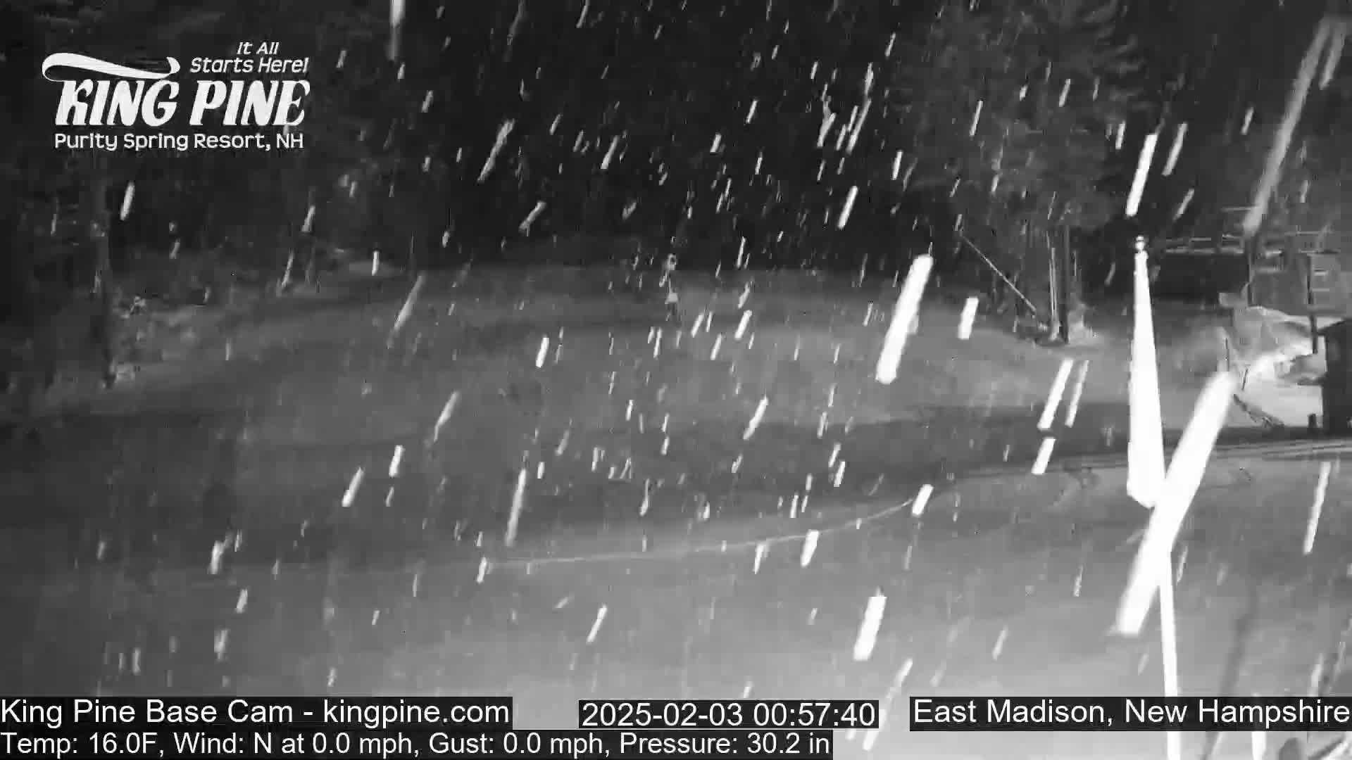 A nighttime scene of snow falling in an outdoor area.