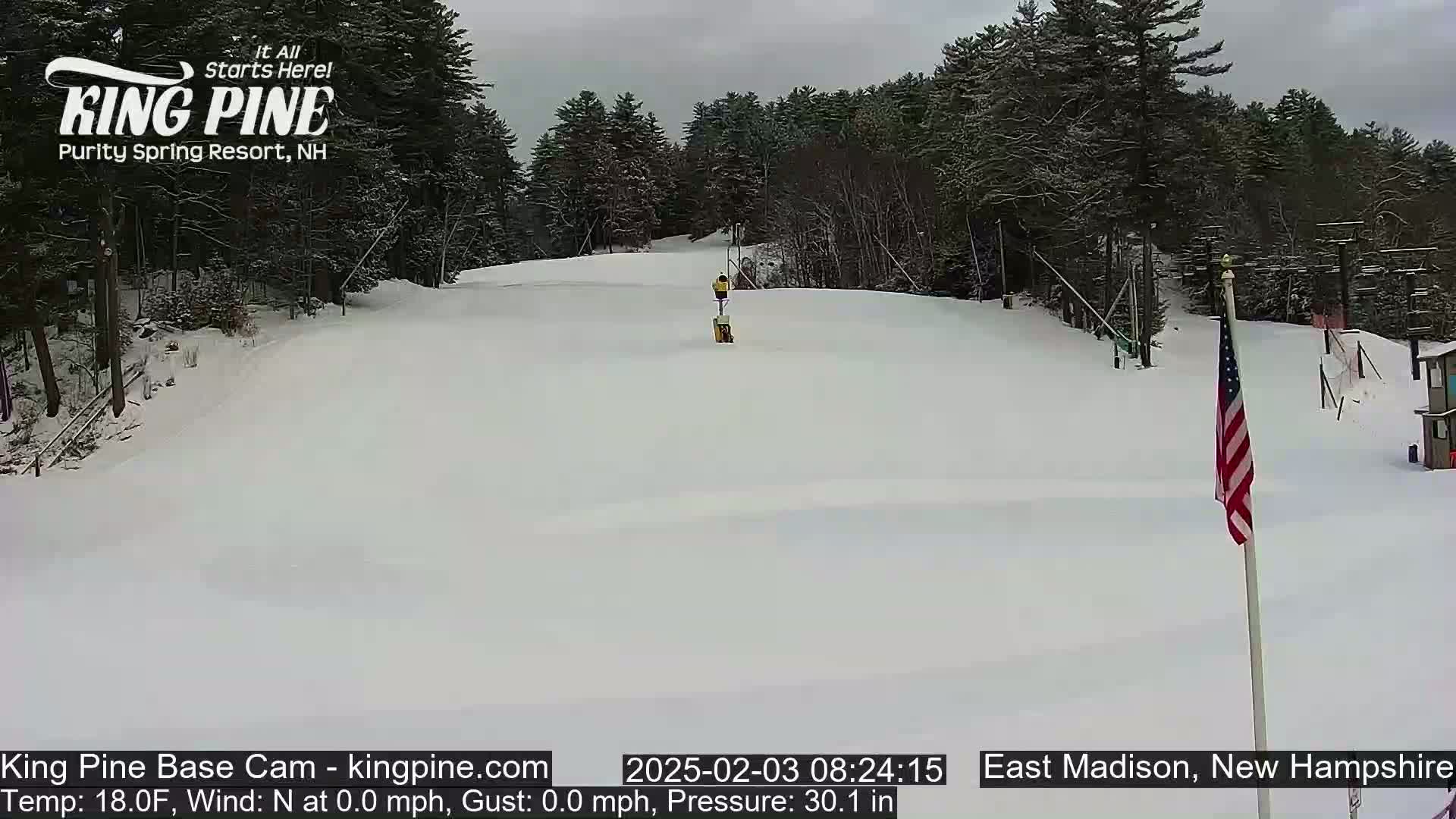 A snow-covered ski slope is visible, with a person skiing down a hill, under an overcast sky.