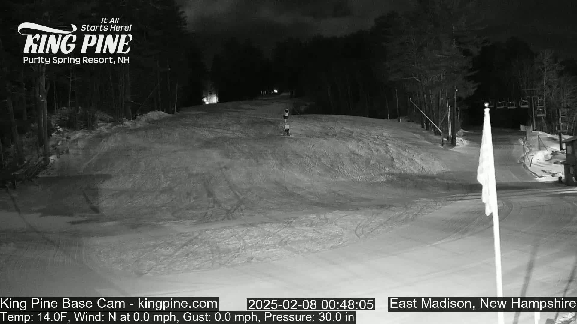 A snow-covered ski slope at night, illuminated by artificial light.
