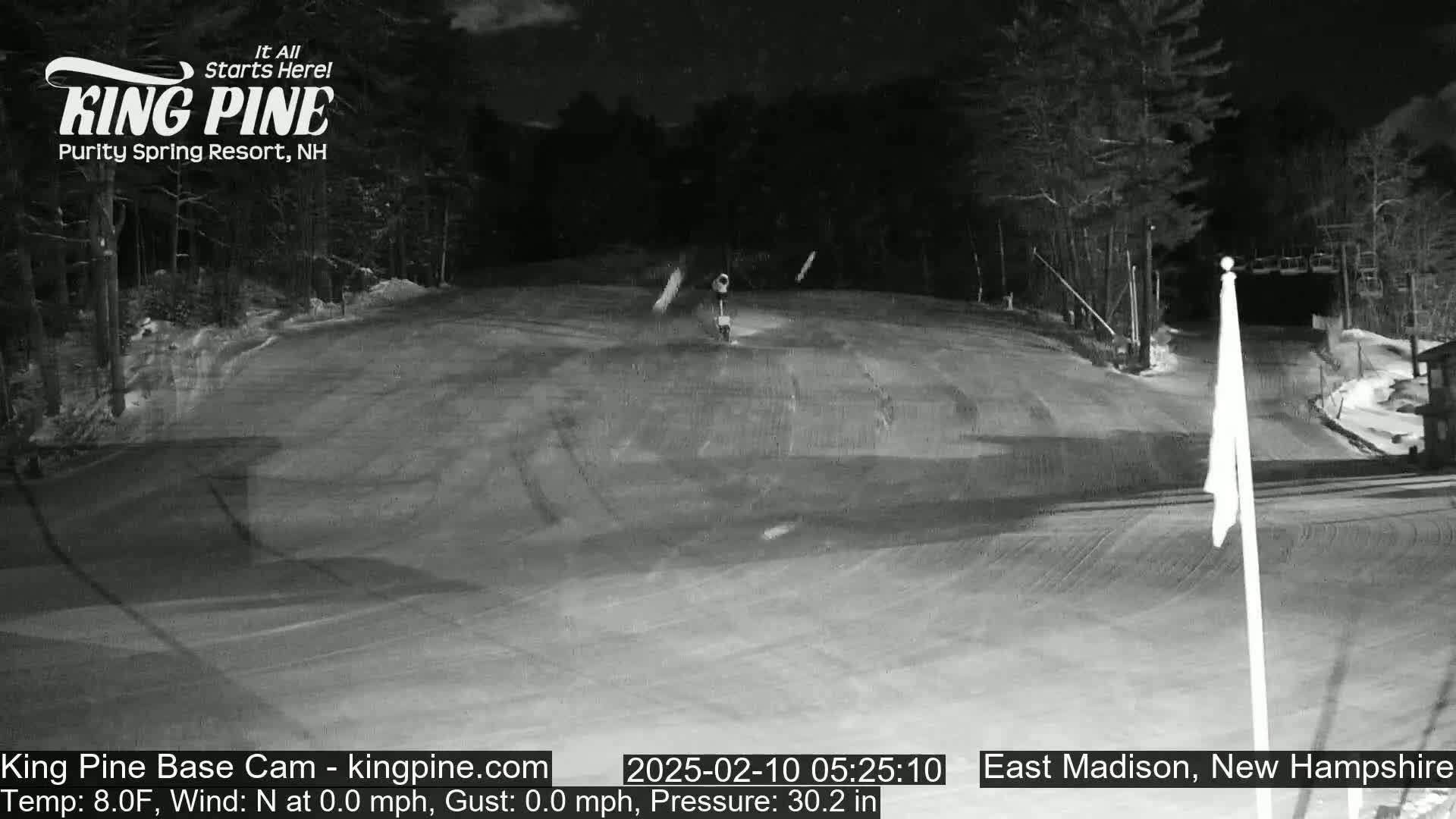 A nighttime view of a snow-covered ski slope with calm conditions.