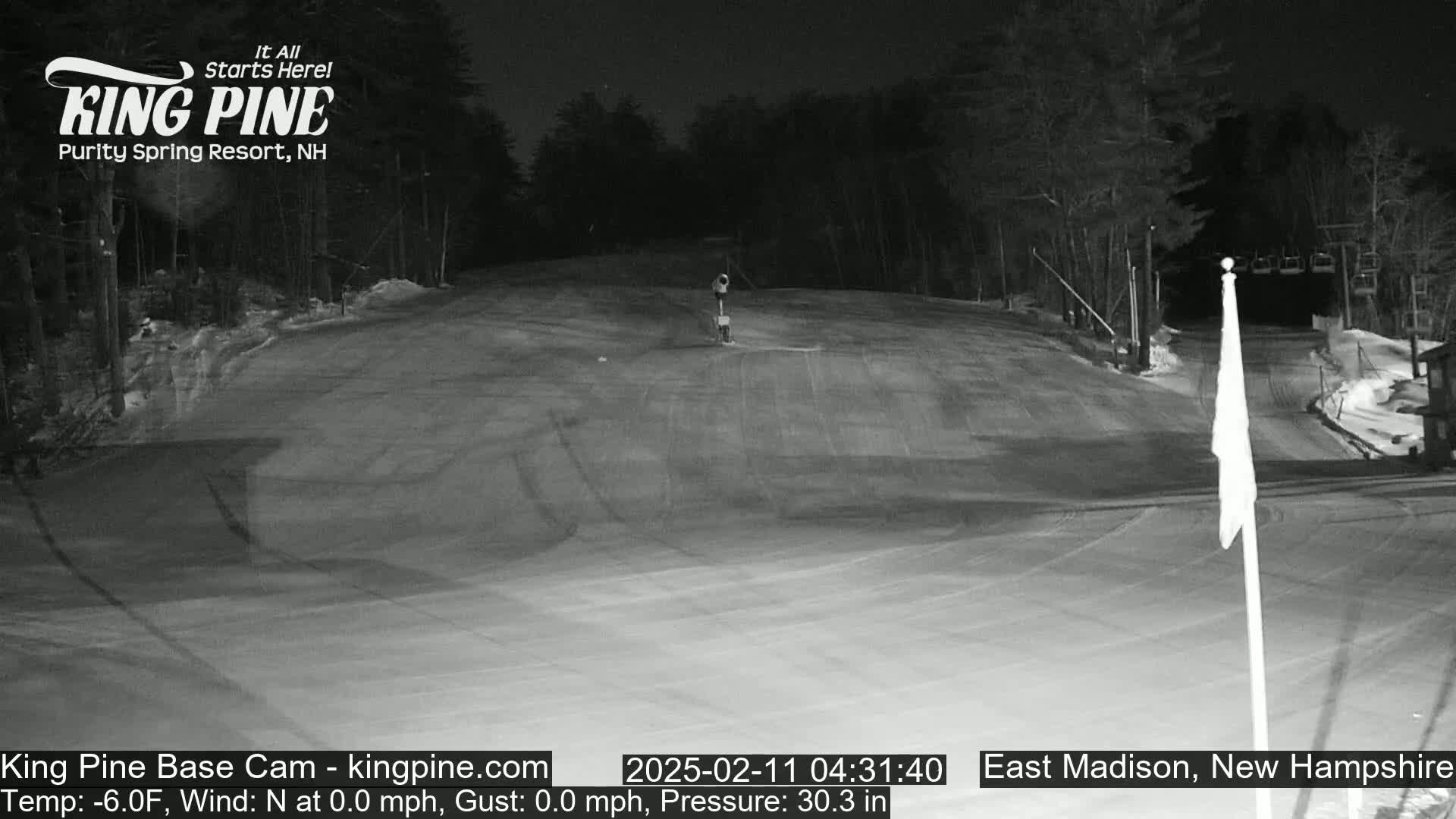 A snow-covered ski slope at night is illuminated by artificial light.