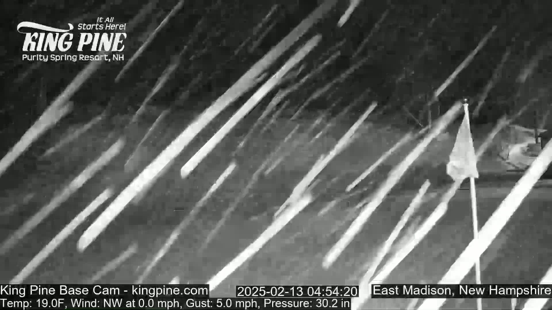 A nighttime scene of heavy snowfall with a partially visible white flag in the foreground.