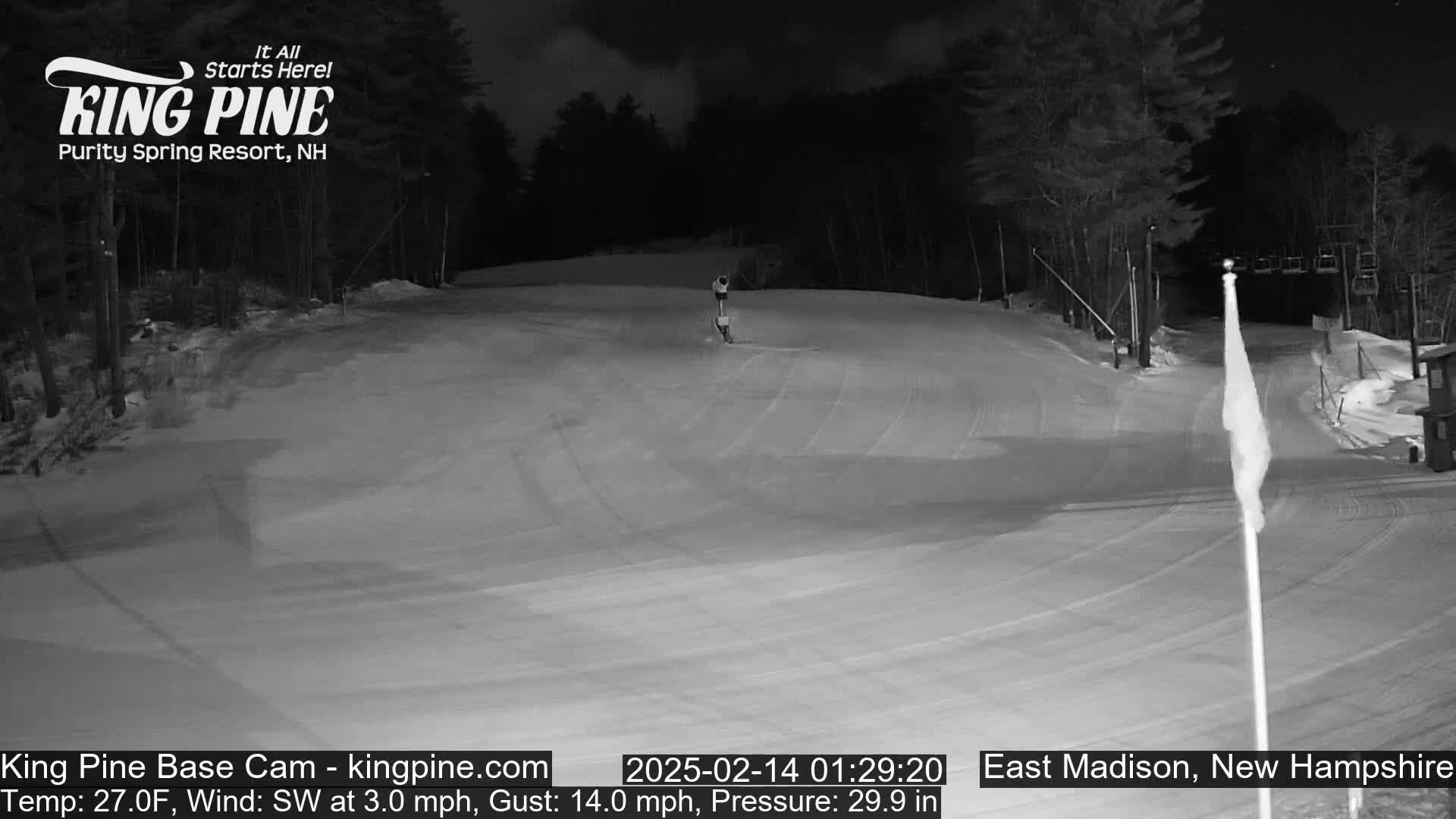 A nighttime, snow-covered ski slope is illuminated, with a slight southwest wind.