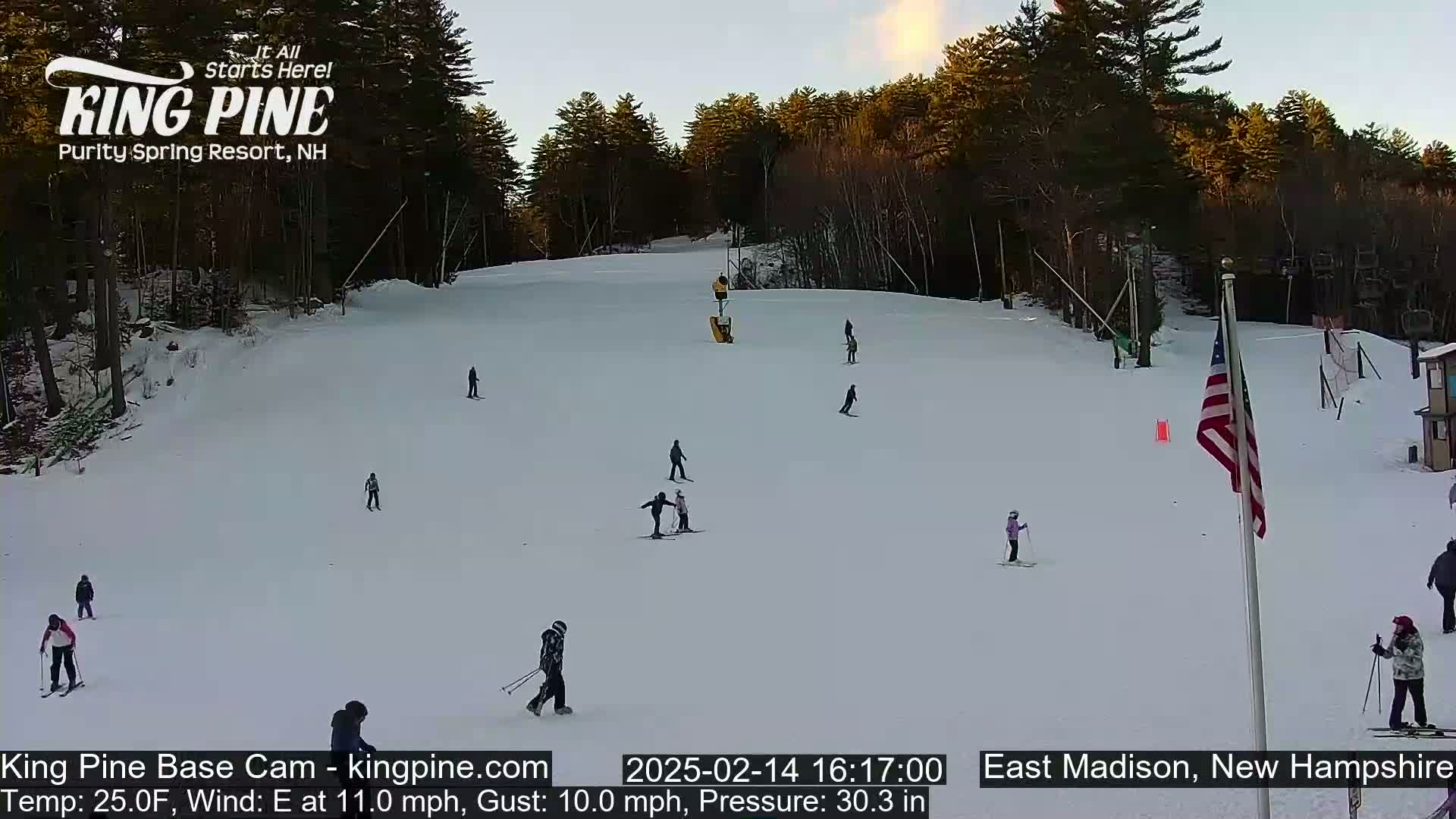 Several skiers and snowboarders are on a snow-covered ski slope under a twilight sky.