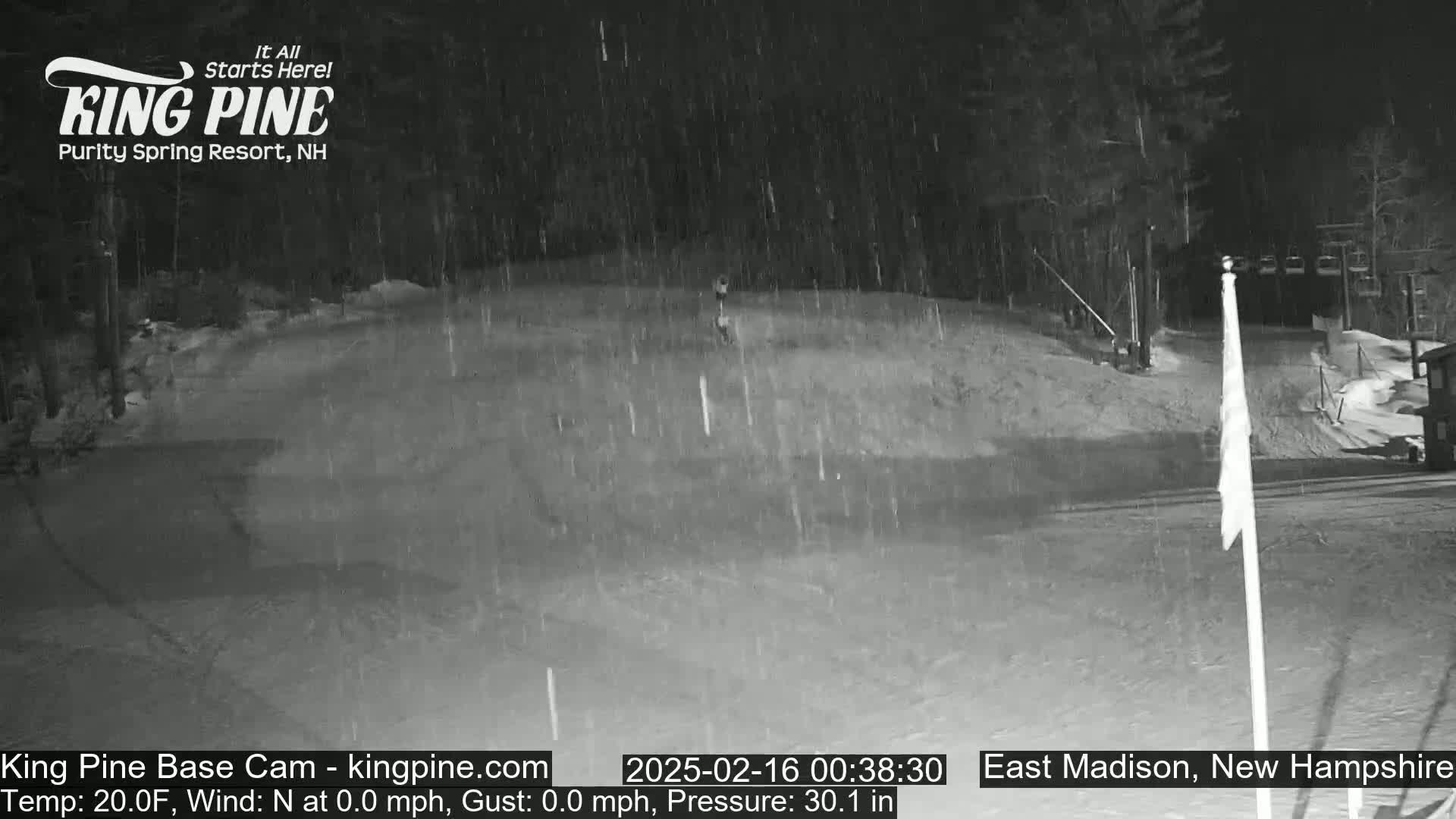 A snow-covered ski slope at night with light snowfall.