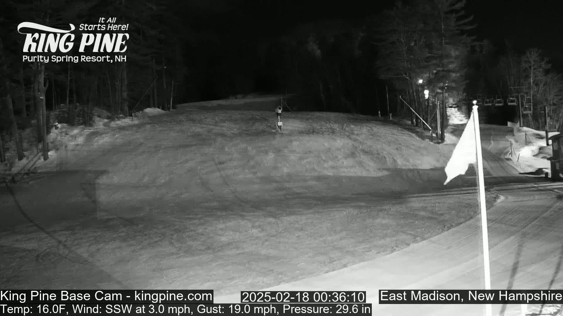 A nighttime, snow-covered ski slope with a chairlift in the background, under a wind of 3 mph from the south-southwest, gusting to 19 mph.