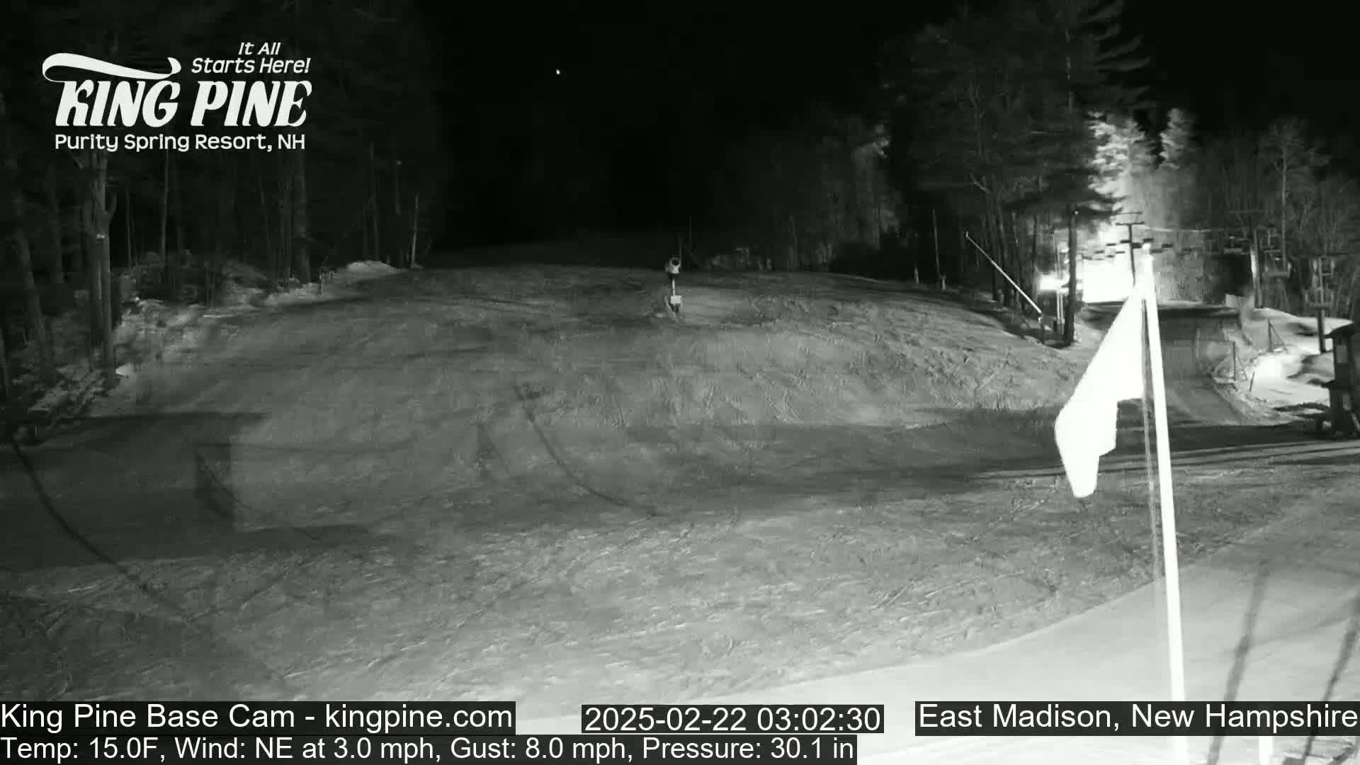 A nighttime, snow-covered ski slope is visible under a clear sky.