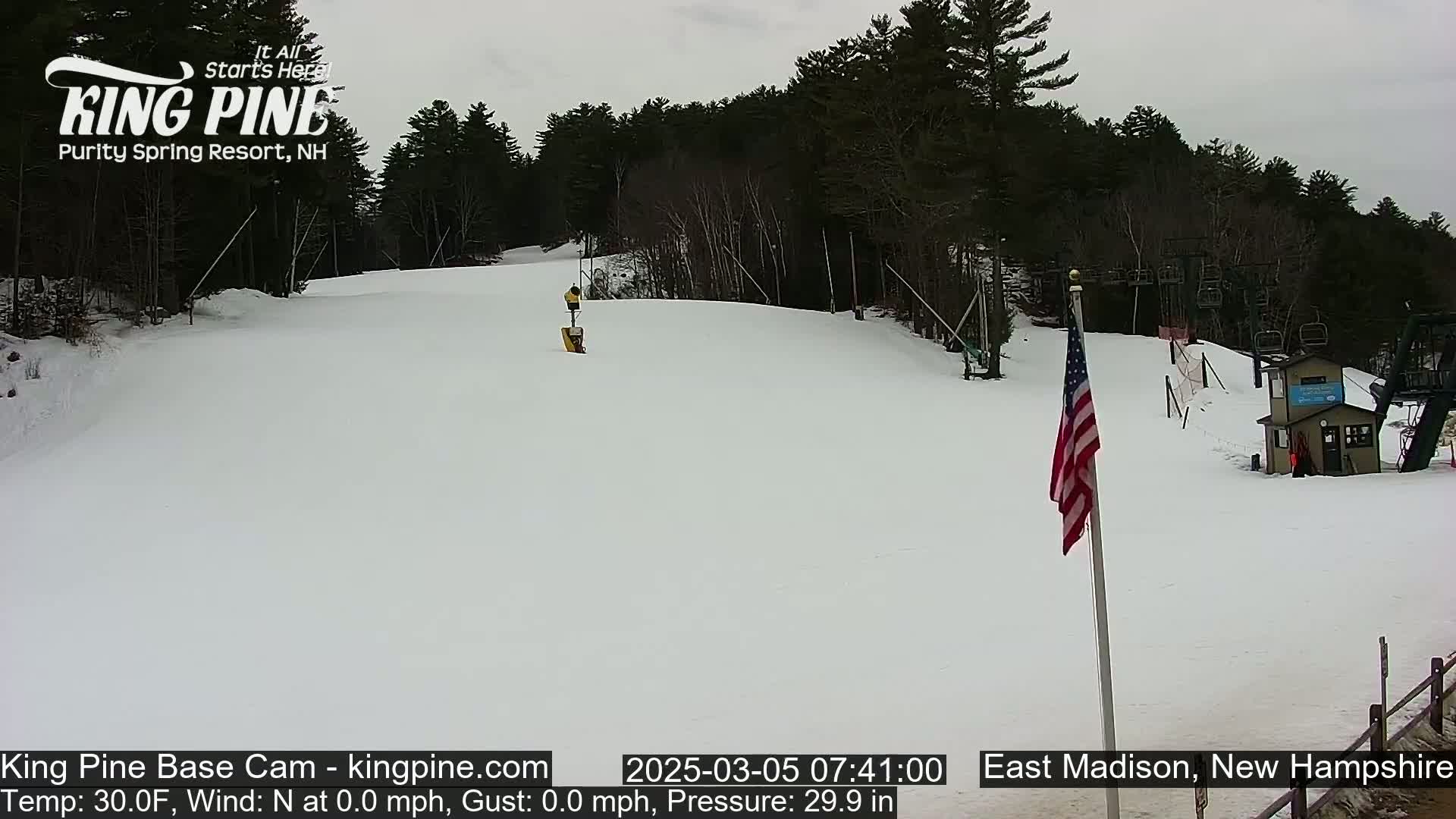 A snow-covered ski slope with a chairlift and a small building is visible under an overcast sky.