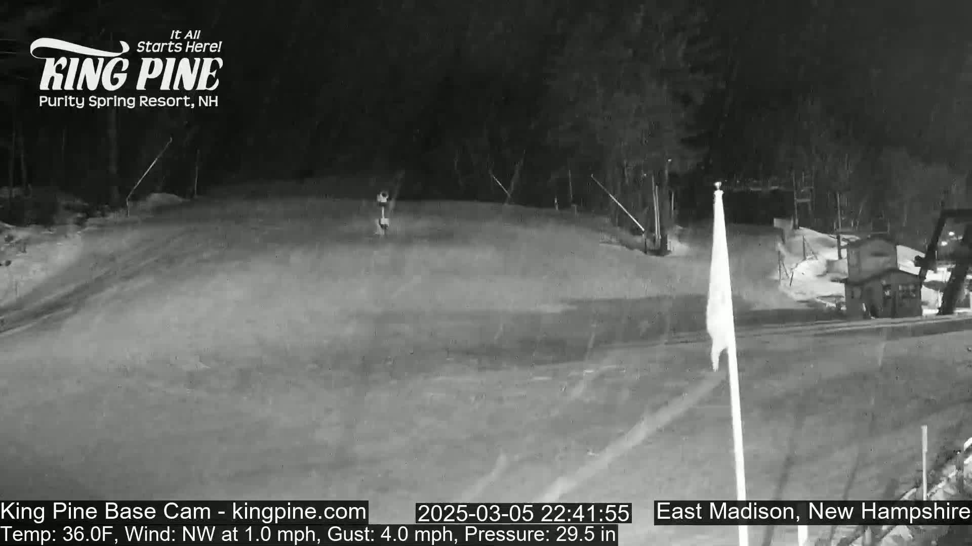 A nighttime, snow-covered ski slope is visible, with a gentle northwest wind.