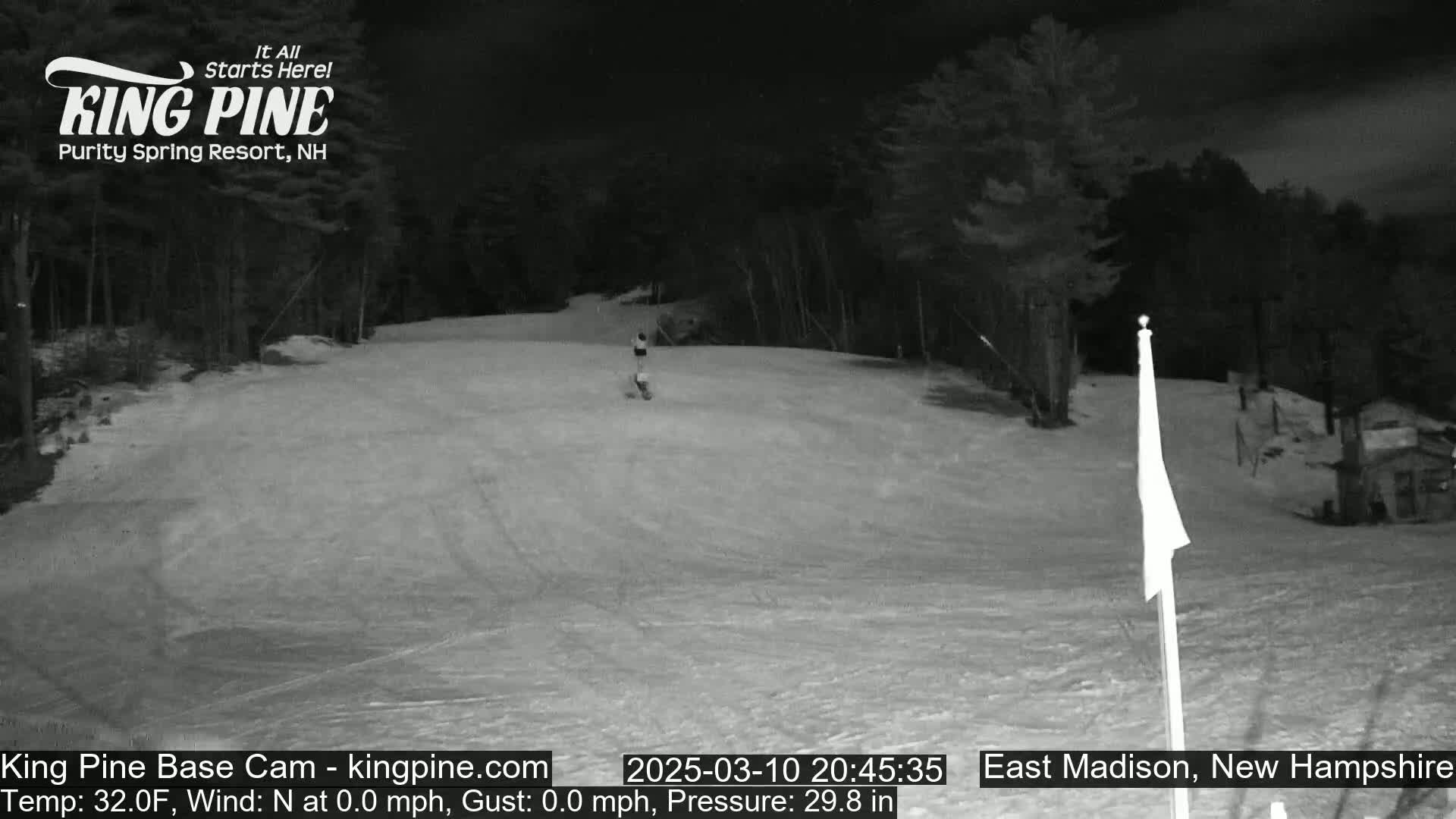 A snowboarder descends a snow-covered slope at night under a clear sky.