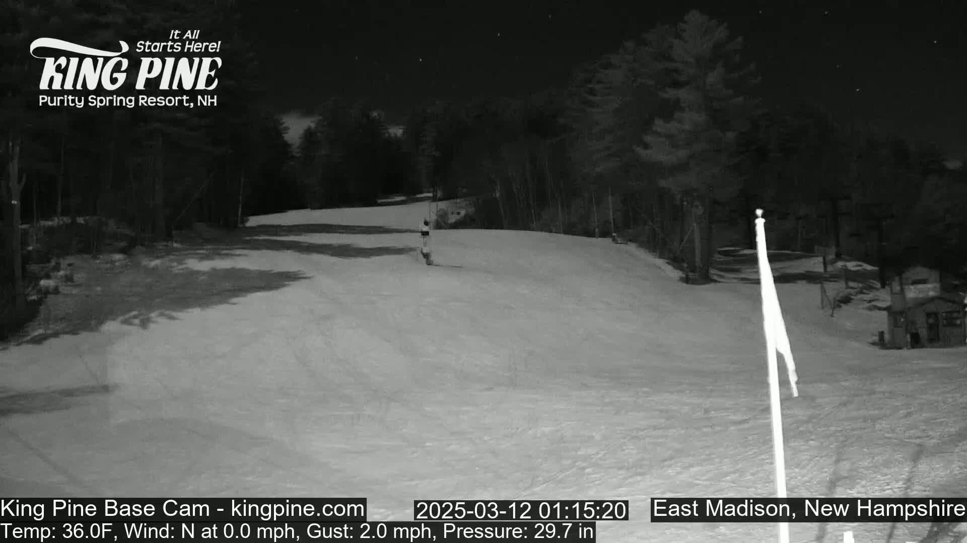 A nighttime view of a snow-covered ski slope under a clear, starry sky.