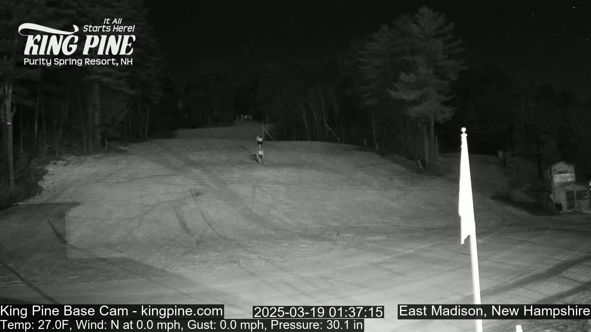 A nighttime, snow-covered slope with a single person skiing down it under a clear sky.