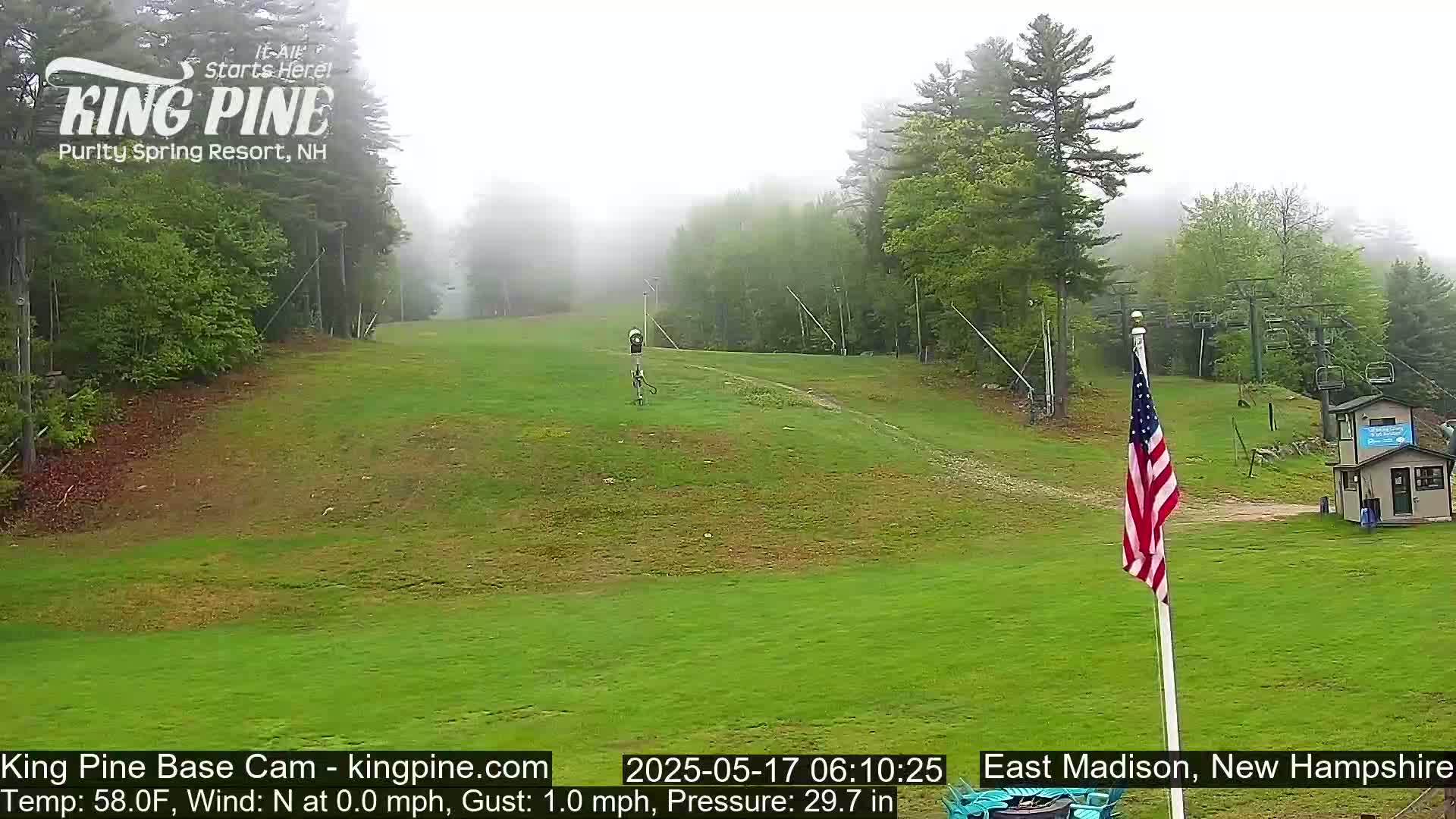 A grassy hill with a ski lift and an American flag is visible in foggy conditions.