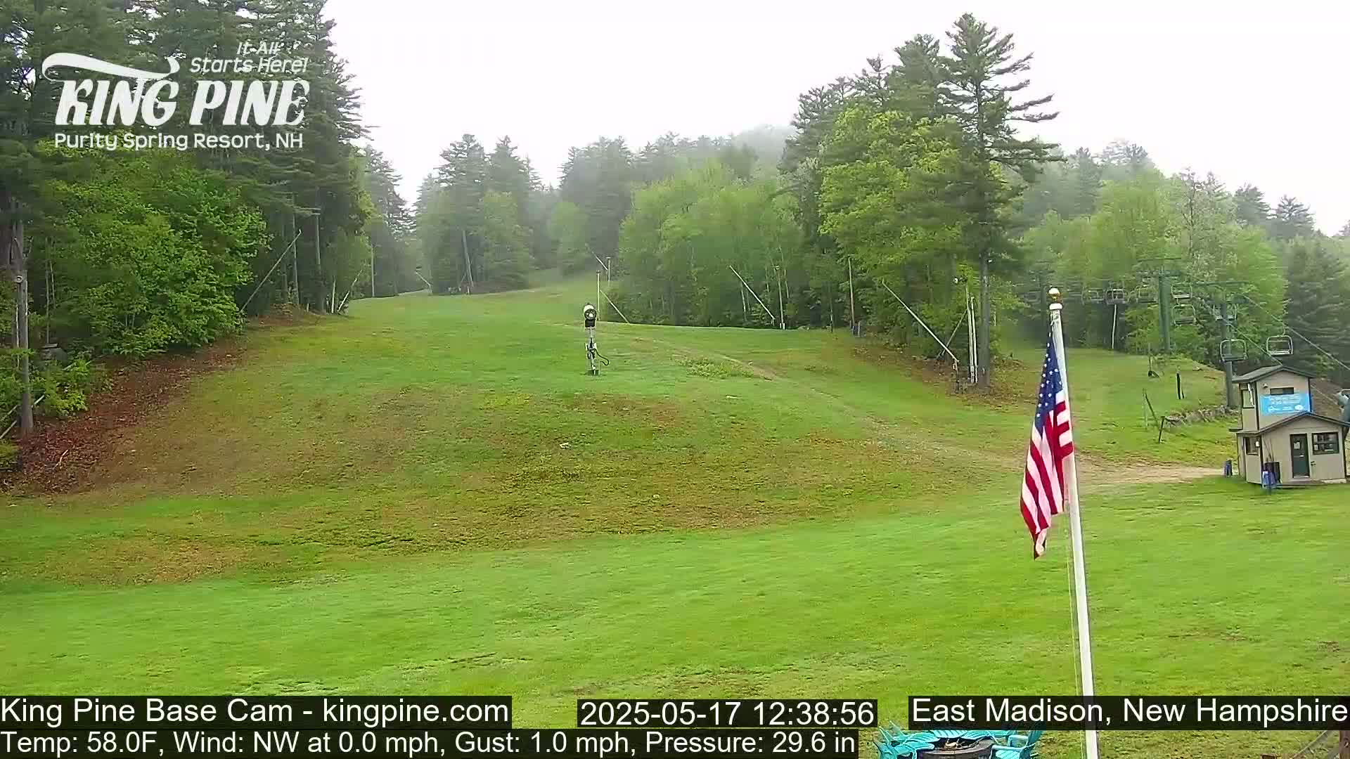 A grassy hill with a ski lift and a small building is visible on an overcast day.