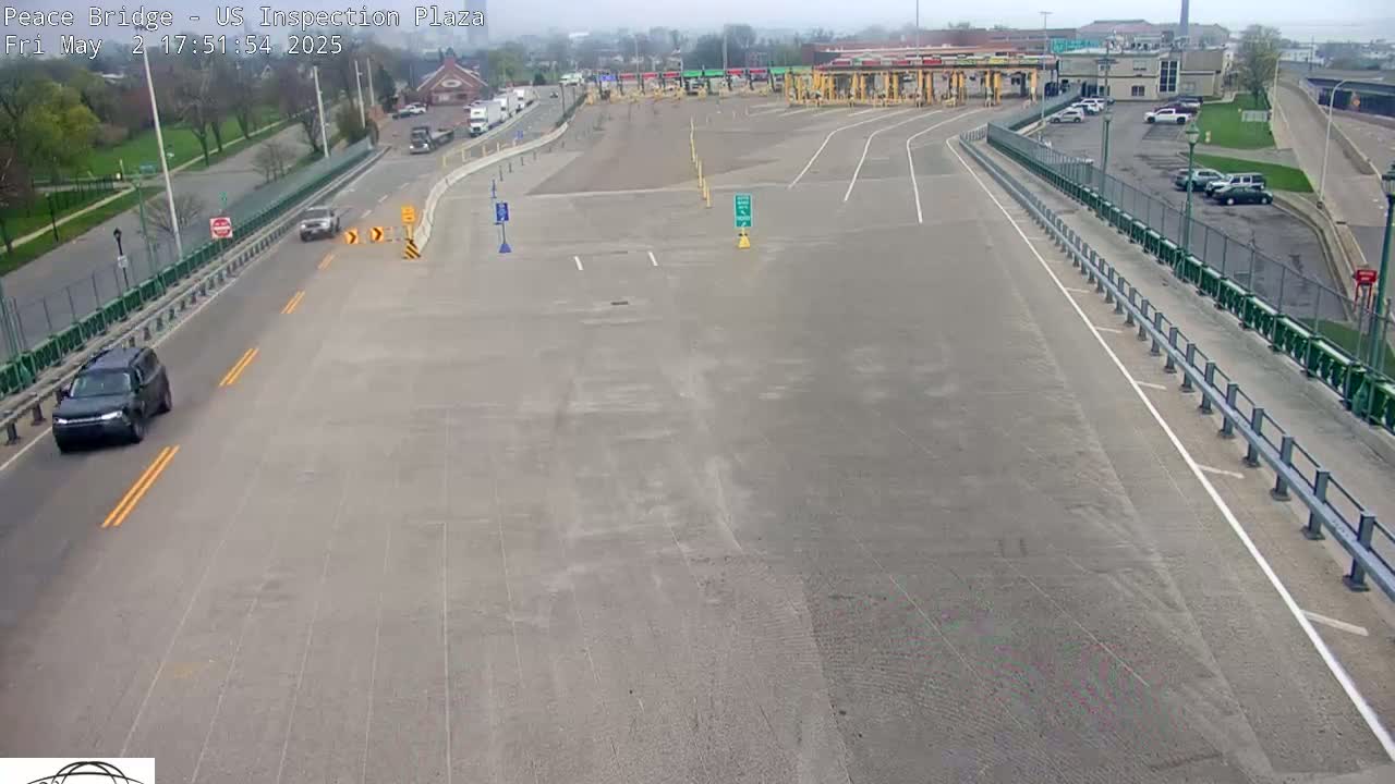 A mostly empty US inspection plaza with a few cars, under an overcast sky.