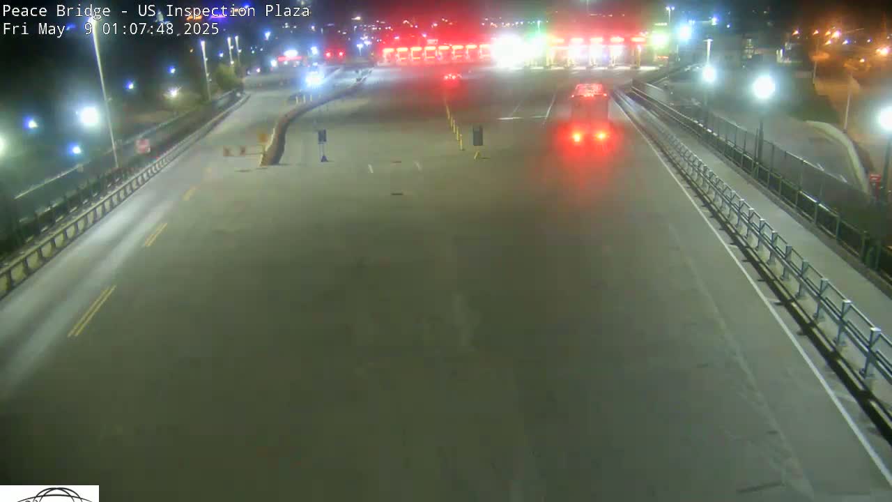 A nighttime overhead view shows a mostly empty roadway leading to a border inspection plaza with a few vehicles visible.