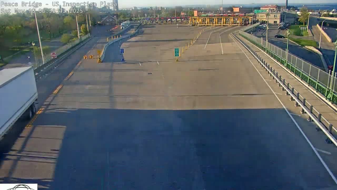 An empty inspection plaza with a few vehicles in the distance, under a sunny sky.