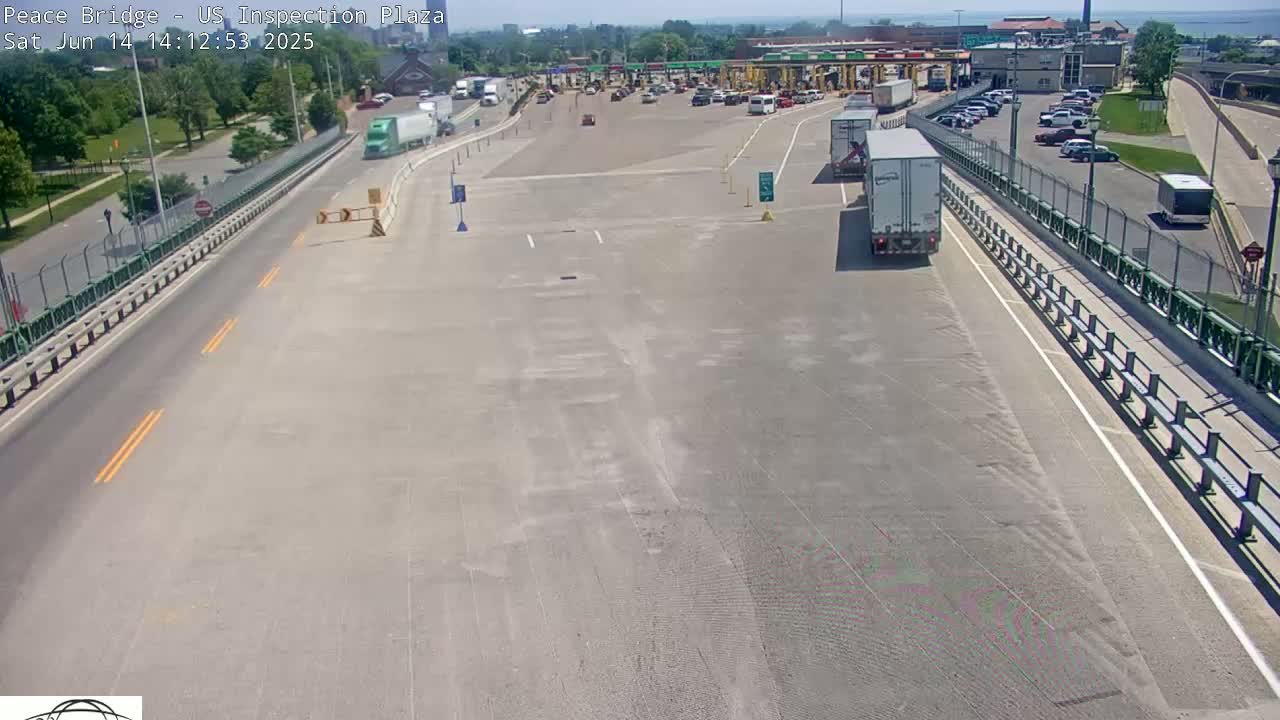 A mostly empty highway inspection plaza on a sunny day with several cars and trucks present.