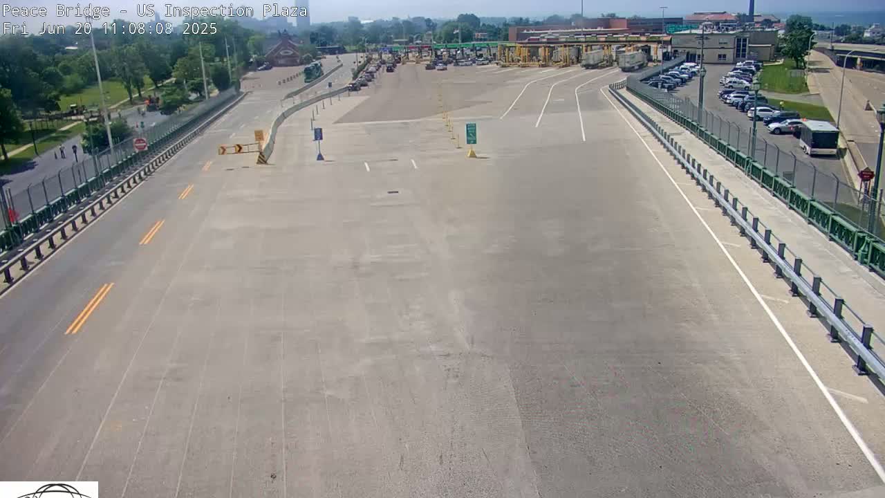 A mostly empty US inspection plaza with several cars and trucks present on a sunny day.
