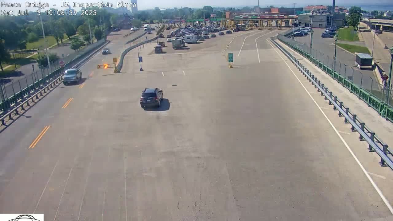 A mostly empty highway and inspection plaza with a few vehicles visible on a sunny day.