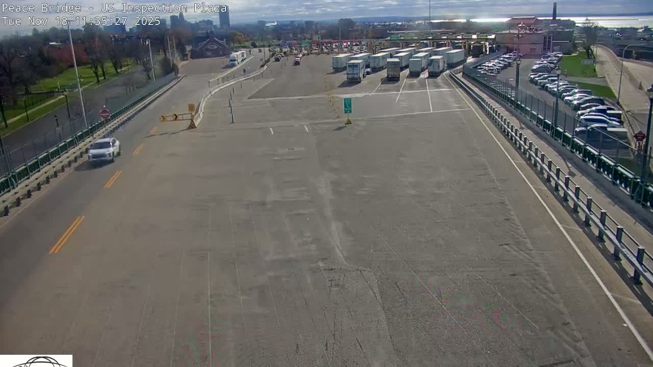 A nighttime, overhead view of a roadway with several vehicles, including a truck and cars, at a border crossing inspection plaza.