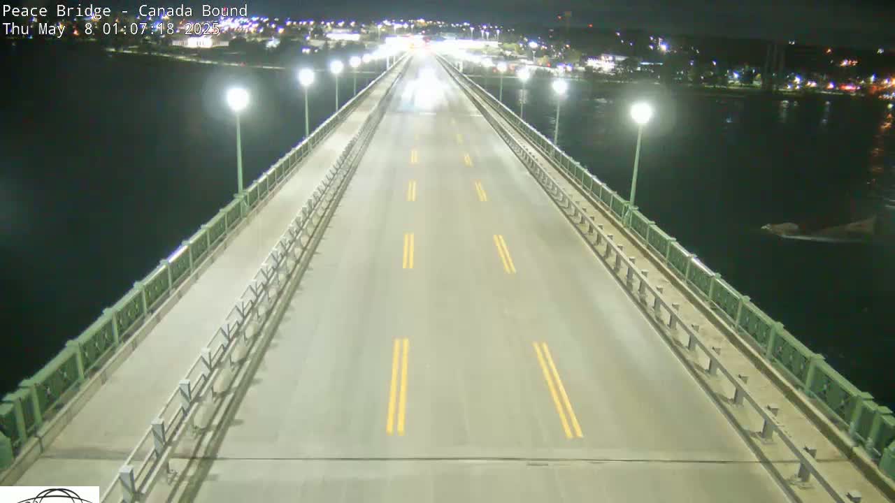 A dark, empty highway stretches across a bridge at night, over dark water.