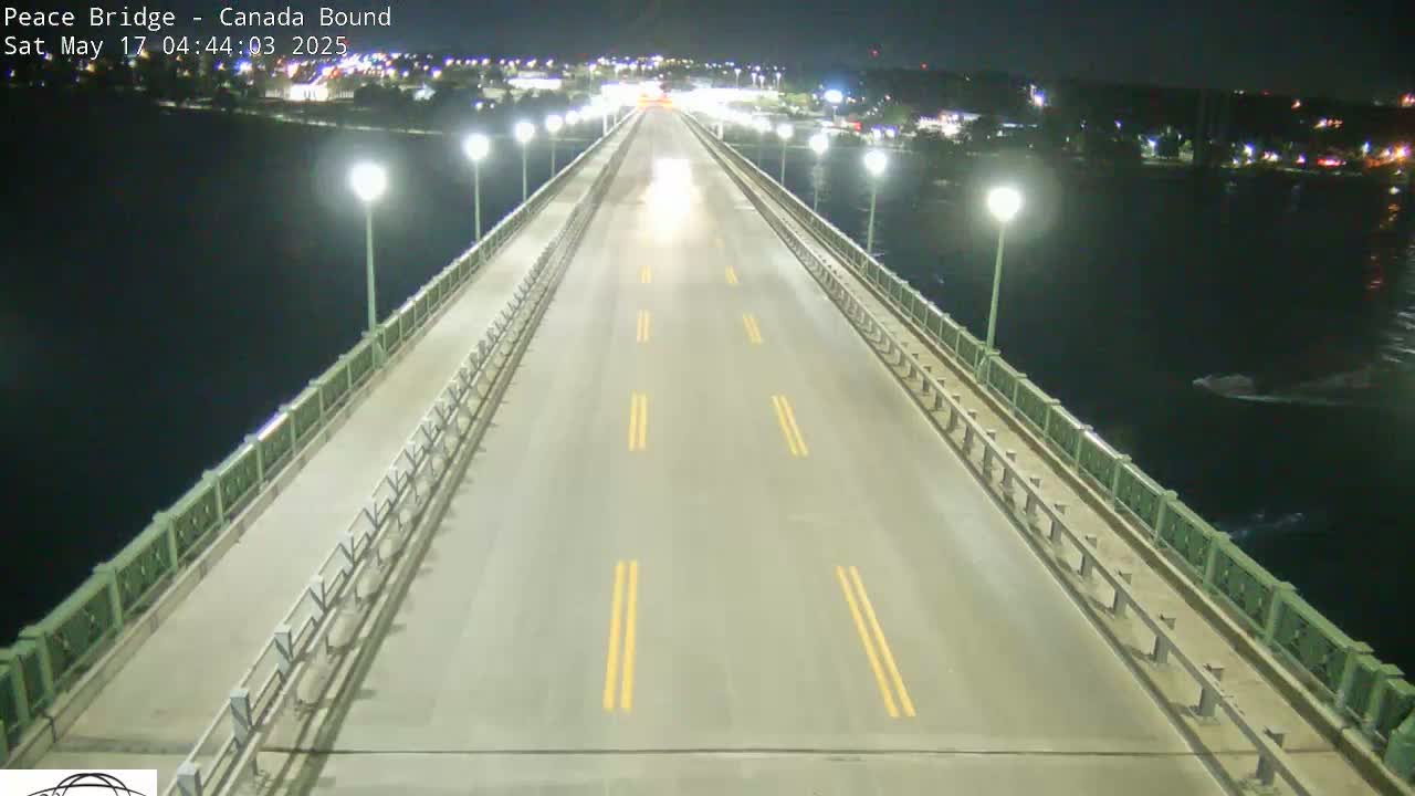 A mostly empty highway stretches across a bridge at night, over dark water, lit by streetlights.