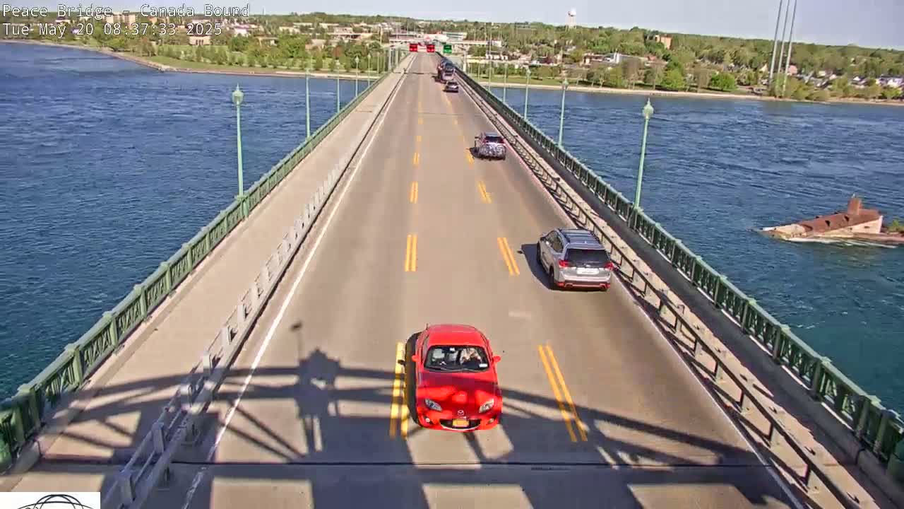 A bridge over blue water on a sunny day with several cars driving across it.